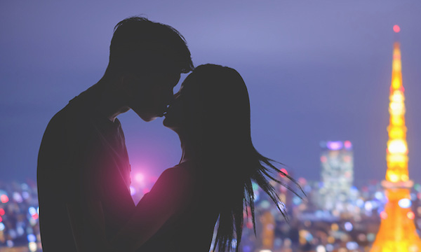 夜景を前にキスする男女