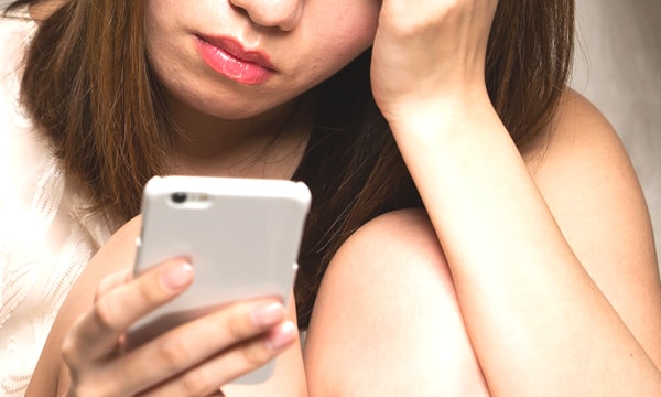 官能小説挿絵:スマートフォンを見ながら思い悩む女性