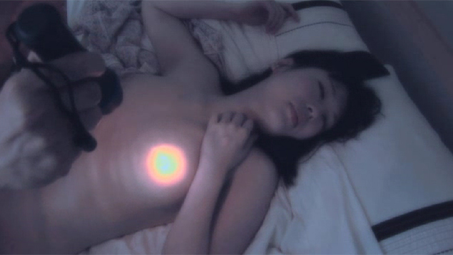 懐中電灯で乳首を照らされる裸の女性