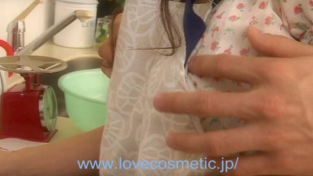 キッチンででエプロン姿の女性の胸を後ろからなでる男性の手